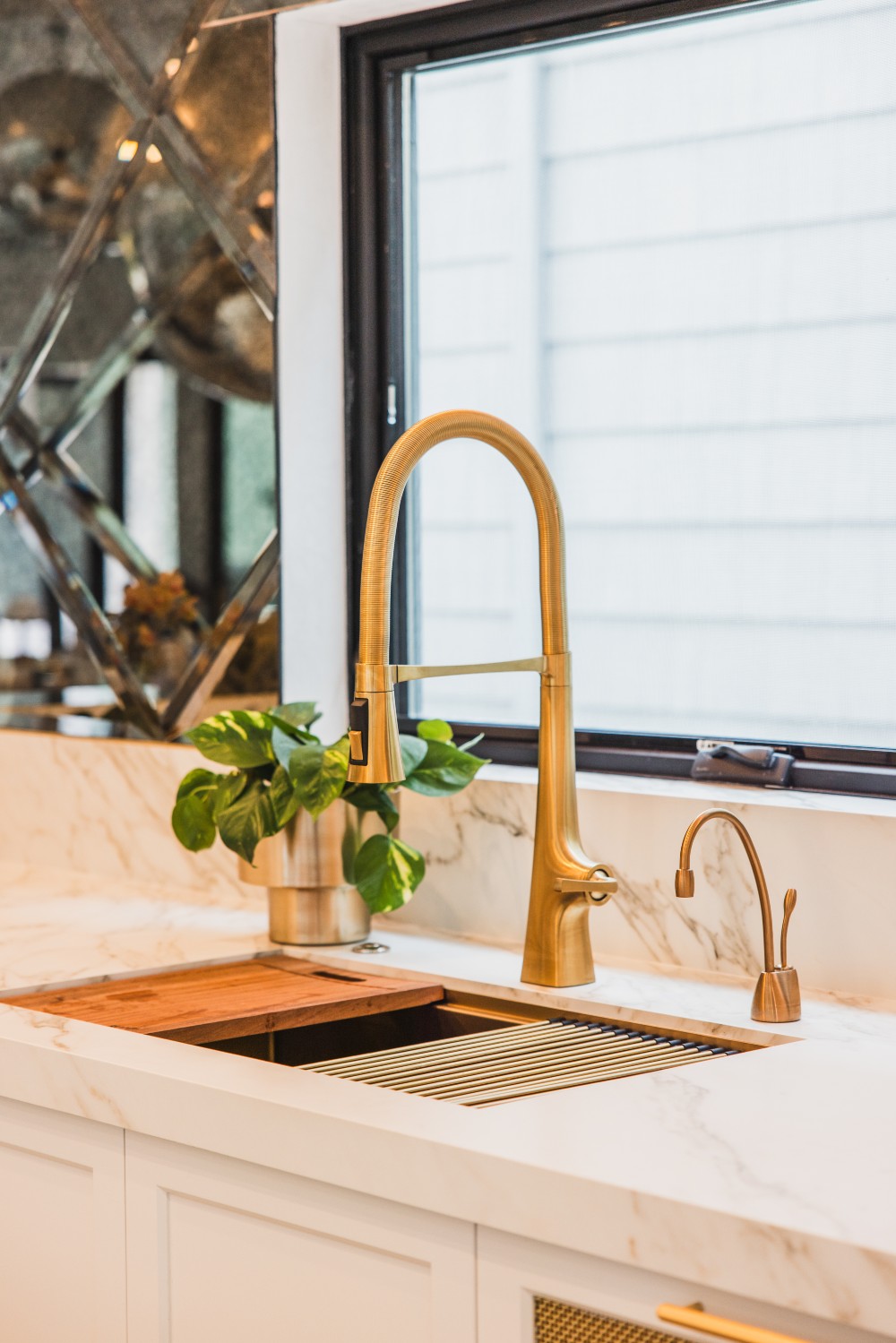 A gold faucet in front of an awning window.