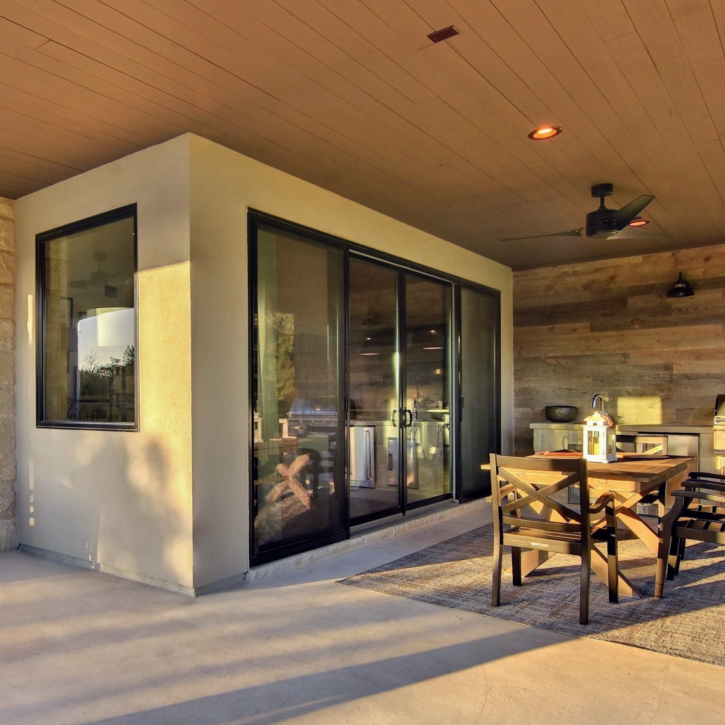 Black modern sliding patio doors looking out to an outdoor kitchen.