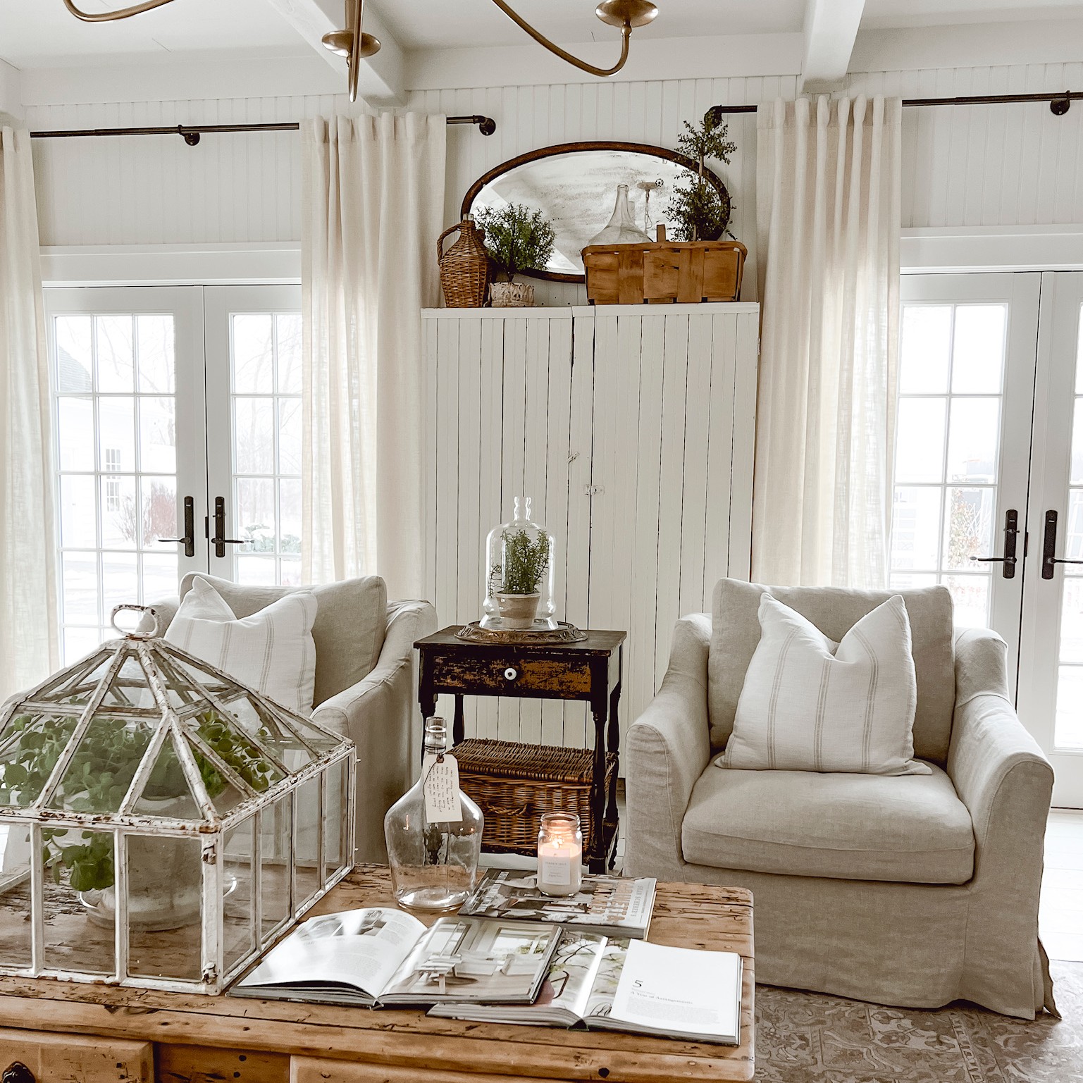 A set of white double doors with equal divided lite grilles. The doors are in the Cozy White Cottage owned by Liz Marie Galvan. The room is white and cozy.